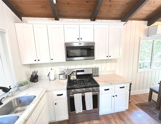 kitchen with light hardwood / wood-style flooring, beamed ceiling, stainless steel appliances, and white cabinetry