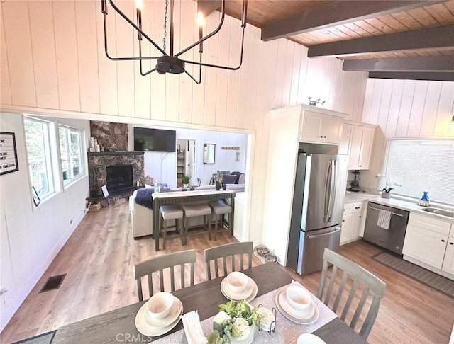 dining space with wood ceiling, light wood-type flooring, a chandelier, and wood walls