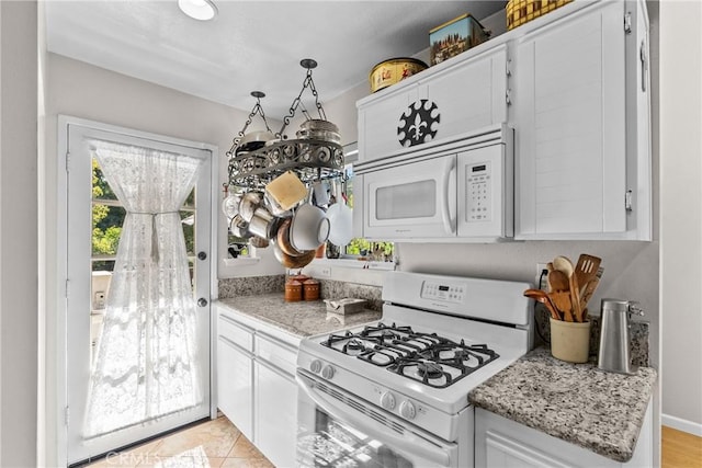 kitchen with white cabinets, light tile patterned floors, white appliances, and light stone counters