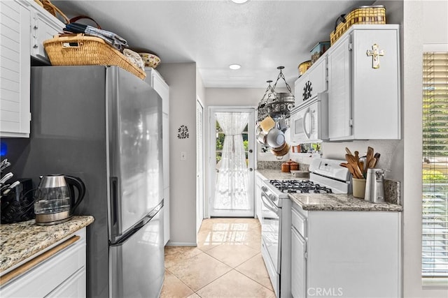 kitchen with white cabinets, white appliances, light stone counters, and a healthy amount of sunlight