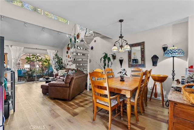 dining area with hardwood / wood-style floors, an inviting chandelier, and track lighting