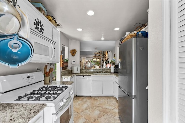 kitchen featuring white appliances, light stone counters, white cabinetry, and sink