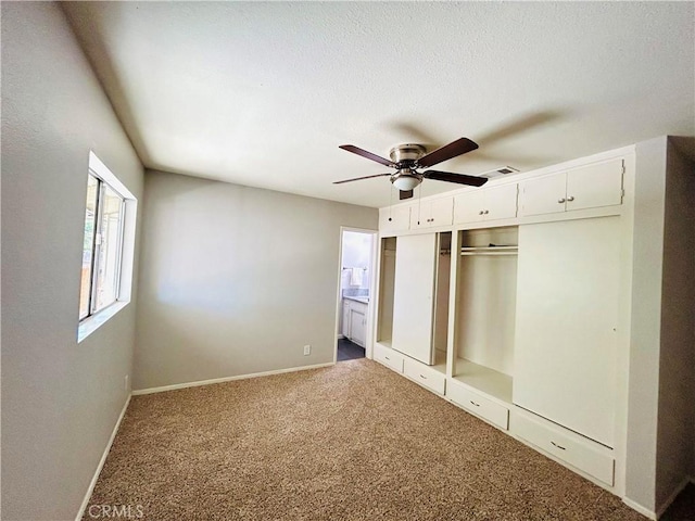 unfurnished bedroom featuring carpet, a closet, ceiling fan, and ensuite bathroom