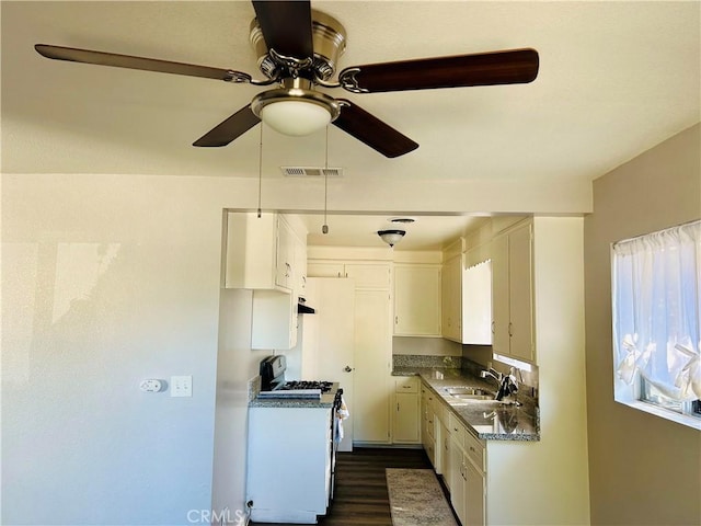 kitchen with dark wood-type flooring, white cabinets, sink, ceiling fan, and white gas stove