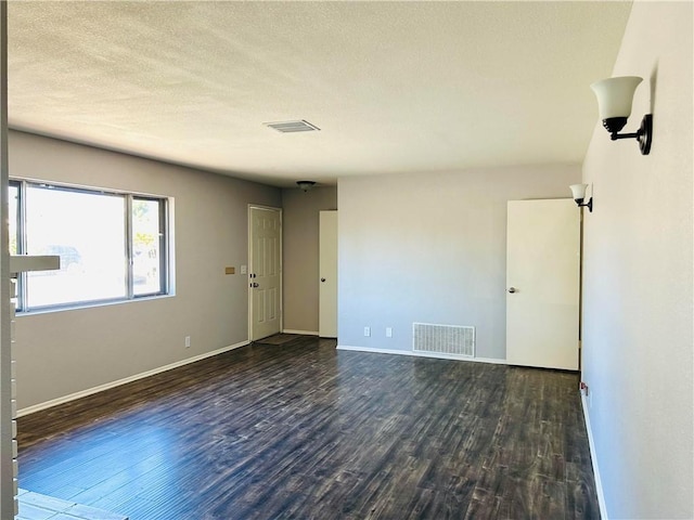 unfurnished room featuring a textured ceiling and dark hardwood / wood-style floors