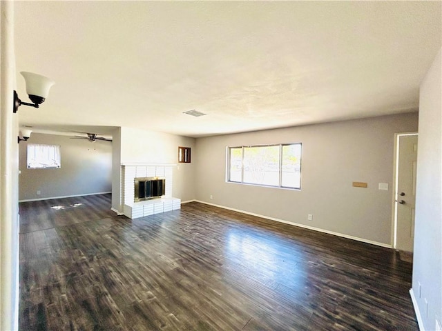 unfurnished living room featuring ceiling fan, a fireplace, and dark hardwood / wood-style floors