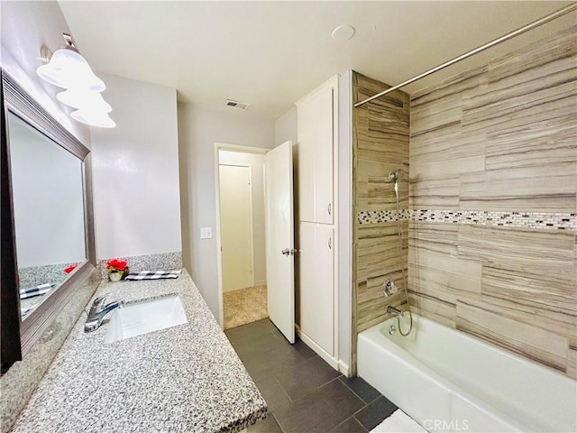 bathroom with tile patterned flooring, tiled shower / bath combo, and vanity