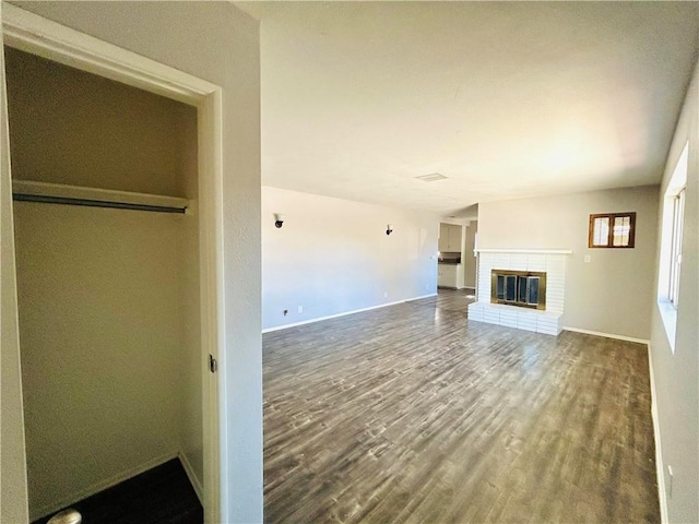 unfurnished living room featuring hardwood / wood-style flooring and a brick fireplace