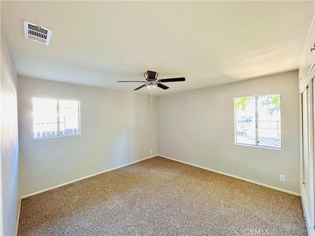 carpeted spare room featuring a wealth of natural light and ceiling fan