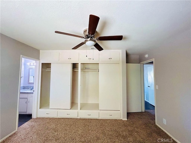 unfurnished bedroom with ensuite bath, ceiling fan, a textured ceiling, a closet, and dark carpet