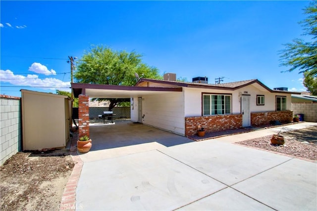 ranch-style house featuring brick siding, fence, driveway, and an attached carport