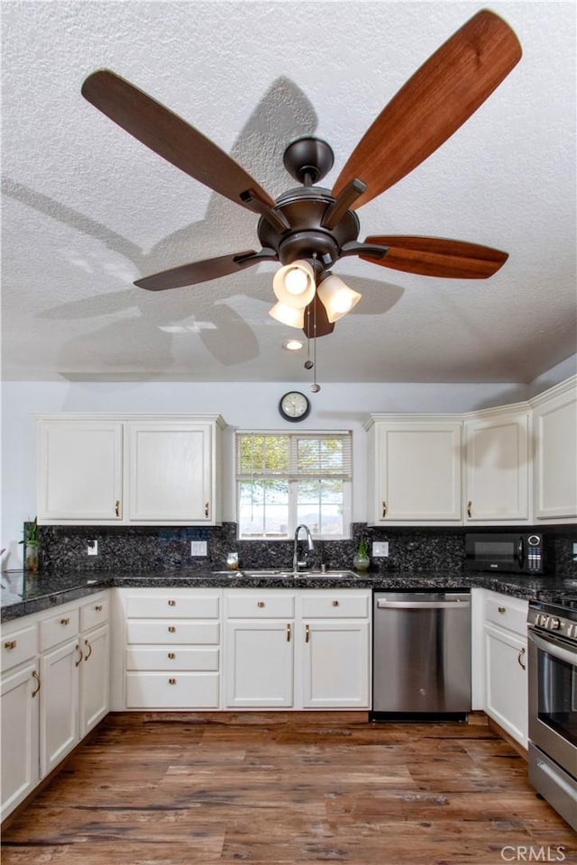 kitchen featuring a sink, decorative backsplash, appliances with stainless steel finishes, and white cabinetry