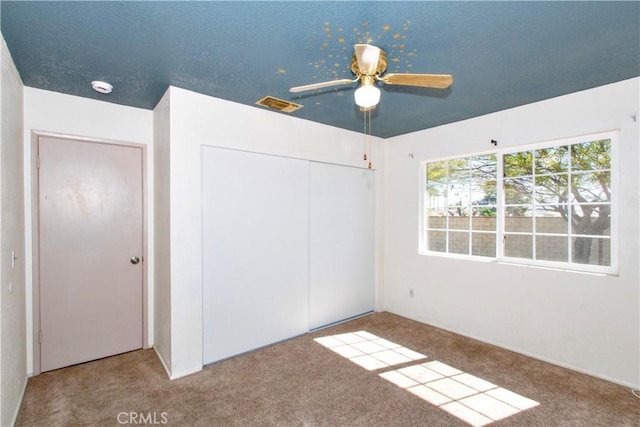 unfurnished bedroom with ceiling fan, visible vents, carpet, and a closet