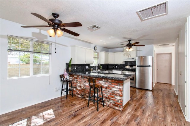 kitchen with visible vents, a ceiling fan, a peninsula, and stainless steel appliances