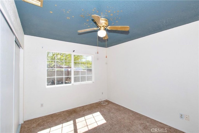 carpeted empty room with a ceiling fan