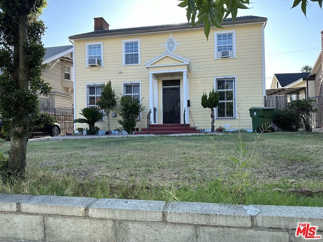 colonial inspired home with cooling unit and a front lawn