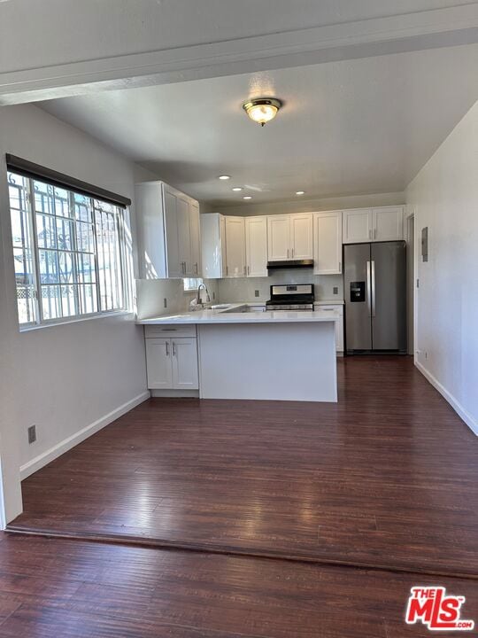 kitchen with kitchen peninsula, white cabinetry, dark wood-type flooring, and appliances with stainless steel finishes