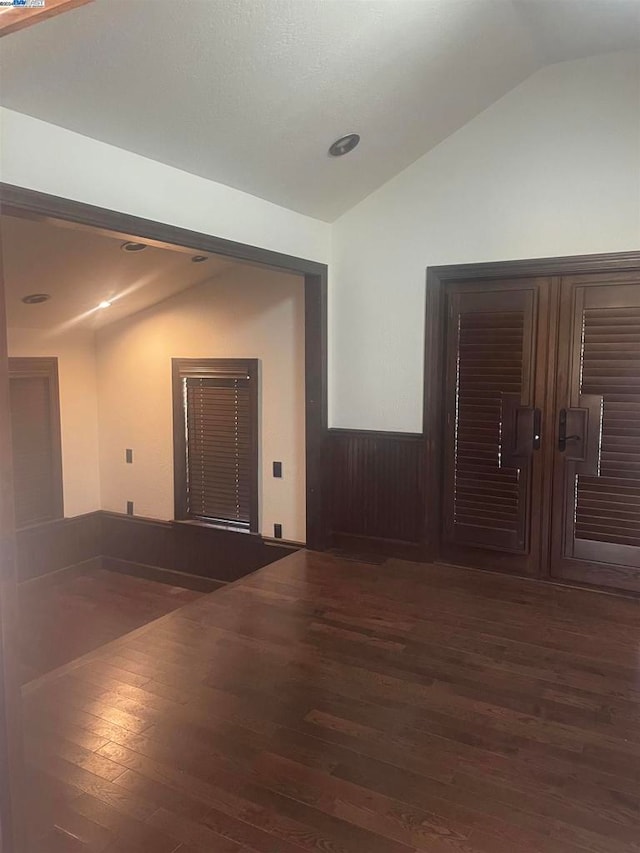 unfurnished room featuring vaulted ceiling and dark wood-type flooring