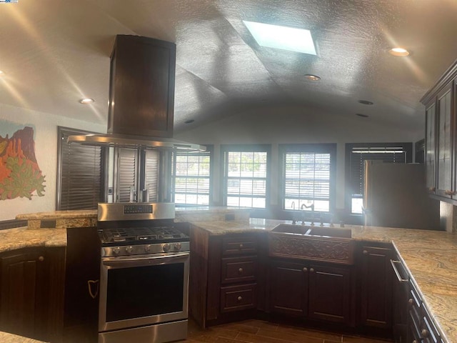 kitchen featuring island exhaust hood, vaulted ceiling, a textured ceiling, and stainless steel range with gas stovetop