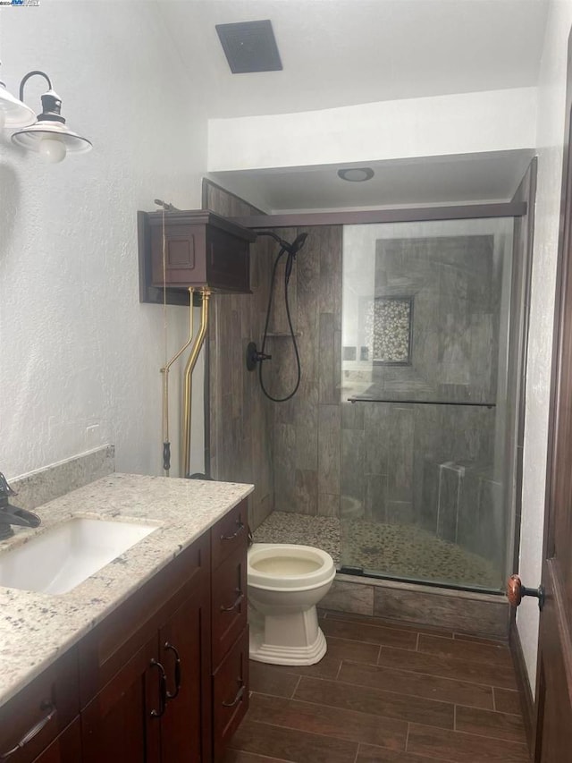 bathroom featuring hardwood / wood-style flooring, vanity, toilet, and a shower with shower door