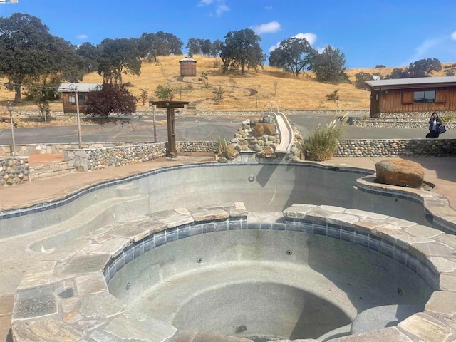 view of swimming pool featuring an in ground hot tub and a rural view