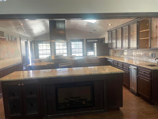 kitchen with dark brown cabinets, lofted ceiling, a kitchen island, and sink