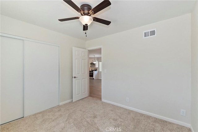 unfurnished bedroom with ceiling fan, a closet, and light carpet