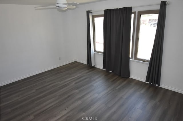 spare room featuring ceiling fan, a healthy amount of sunlight, and dark hardwood / wood-style flooring