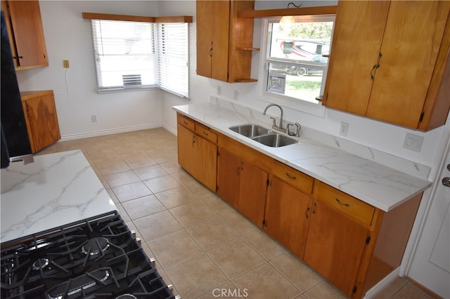 kitchen with light stone counters, light tile patterned floors, and sink