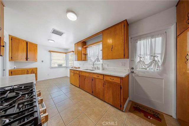 kitchen with brown cabinets, light tile patterned floors, visible vents, and light countertops