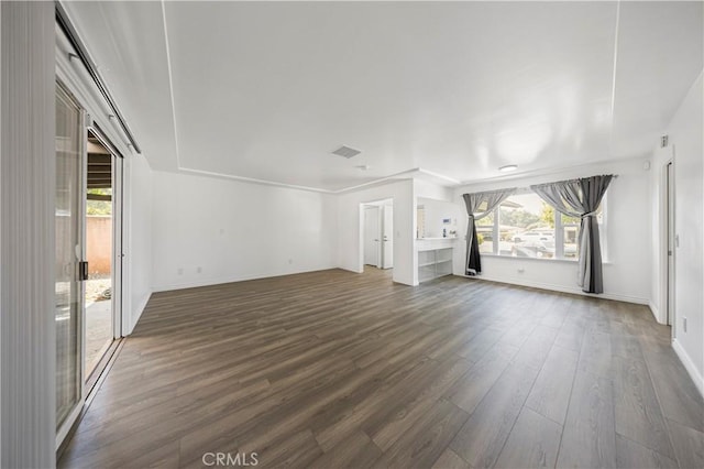 unfurnished living room with baseboards, visible vents, and dark wood finished floors