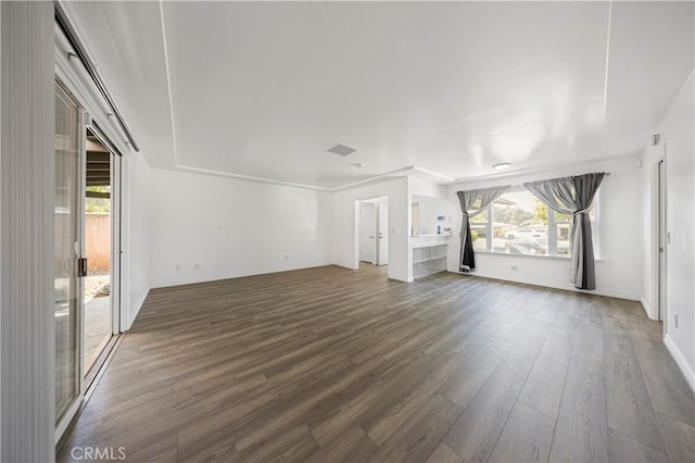 unfurnished living room featuring dark wood finished floors, a wealth of natural light, visible vents, and baseboards