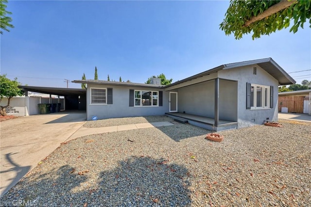 view of front facade with stucco siding, fence, a carport, and concrete driveway
