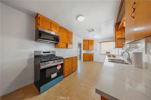 kitchen featuring brown cabinets, stainless steel appliances, visible vents, light tile patterned flooring, and a sink