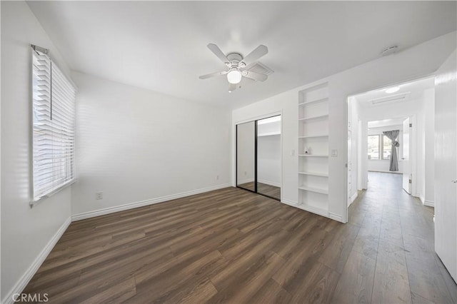 unfurnished bedroom featuring ceiling fan, baseboards, dark wood finished floors, and a closet