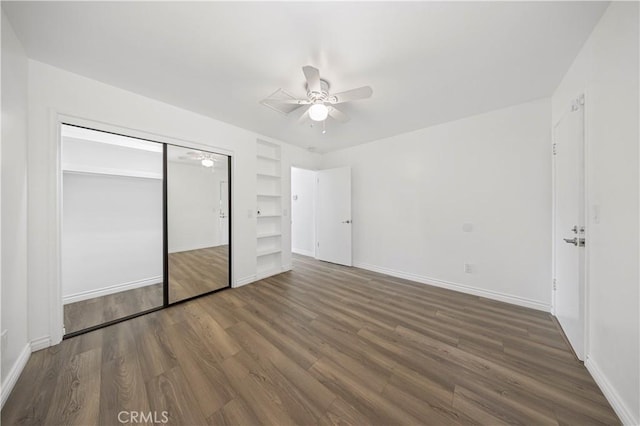 unfurnished bedroom featuring baseboards, a ceiling fan, wood finished floors, and a closet