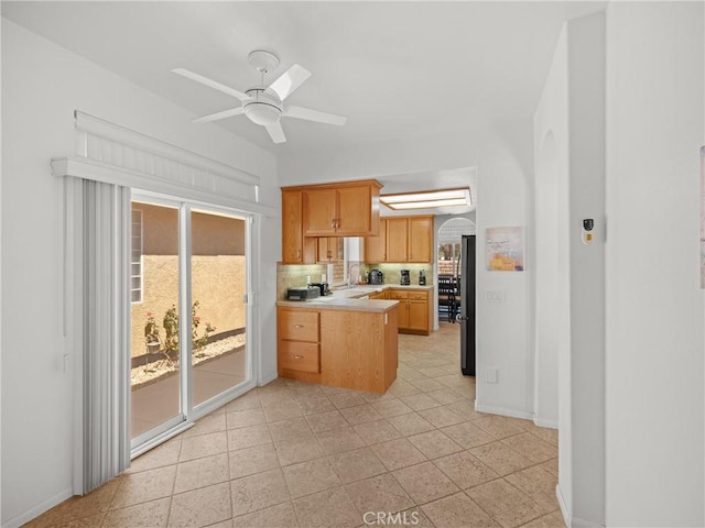 kitchen featuring light brown cabinets, ceiling fan, stainless steel fridge, light tile patterned floors, and tasteful backsplash