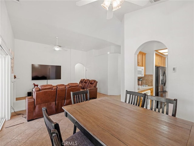 dining room with light tile patterned floors, ceiling fan, and a high ceiling