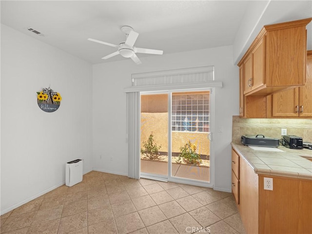 kitchen featuring decorative backsplash, light tile patterned flooring, tile counters, and ceiling fan