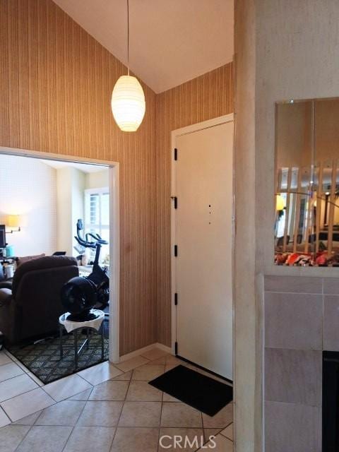 foyer entrance with wooden walls, high vaulted ceiling, and light tile patterned flooring