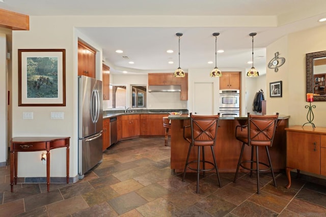 kitchen featuring hanging light fixtures, a kitchen bar, stainless steel appliances, and kitchen peninsula