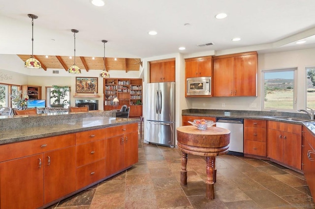 kitchen featuring vaulted ceiling with beams, decorative light fixtures, stainless steel appliances, and sink