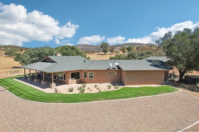 back of house featuring a lawn, a mountain view, and a patio area