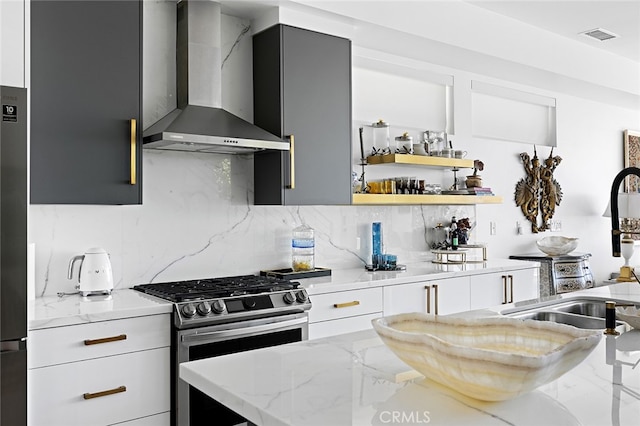 kitchen with light stone countertops, gas stove, wall chimney range hood, and tasteful backsplash