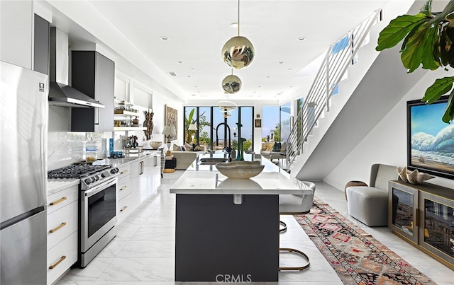 kitchen with stainless steel appliances, a kitchen island with sink, decorative light fixtures, and white cabinets