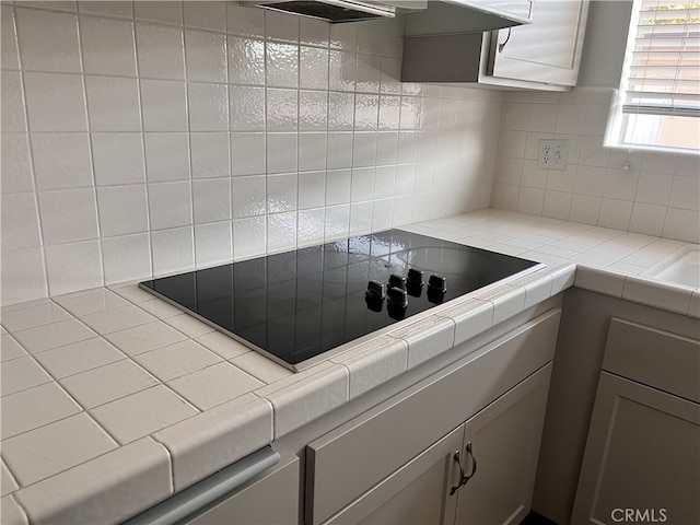 kitchen featuring black electric cooktop, gray cabinets, tile countertops, and decorative backsplash