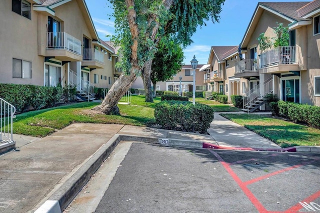 view of property's community with a lawn, uncovered parking, stairway, and a residential view