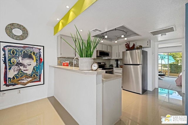 kitchen with kitchen peninsula, tasteful backsplash, stainless steel appliances, light tile patterned floors, and white cabinets