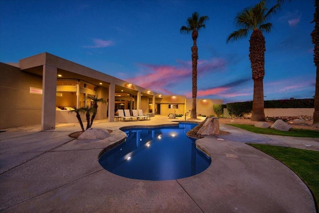 pool at dusk featuring a patio area