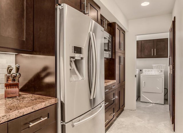 kitchen featuring washer and dryer, light stone countertops, appliances with stainless steel finishes, tasteful backsplash, and dark brown cabinets